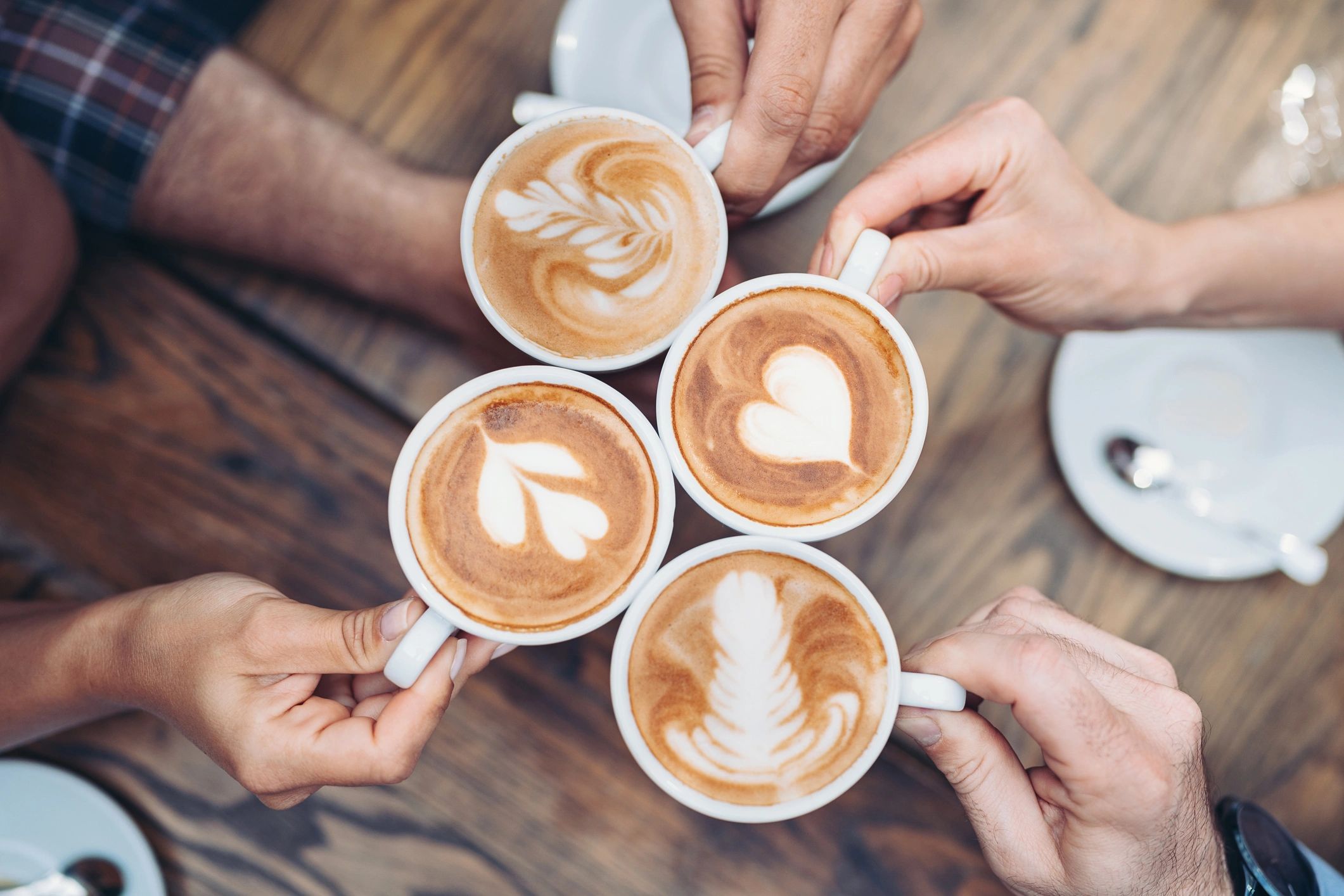 Hands holding warm drinks at a community table